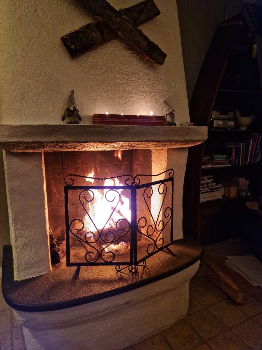 Öppen spis som brinner i stugans vardagsrum.