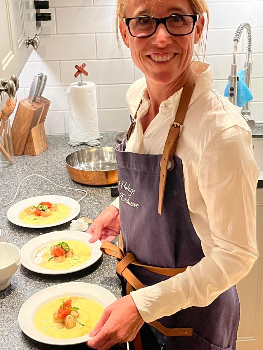 Susanne serverar tallrikar med varm mat i stugans kök.